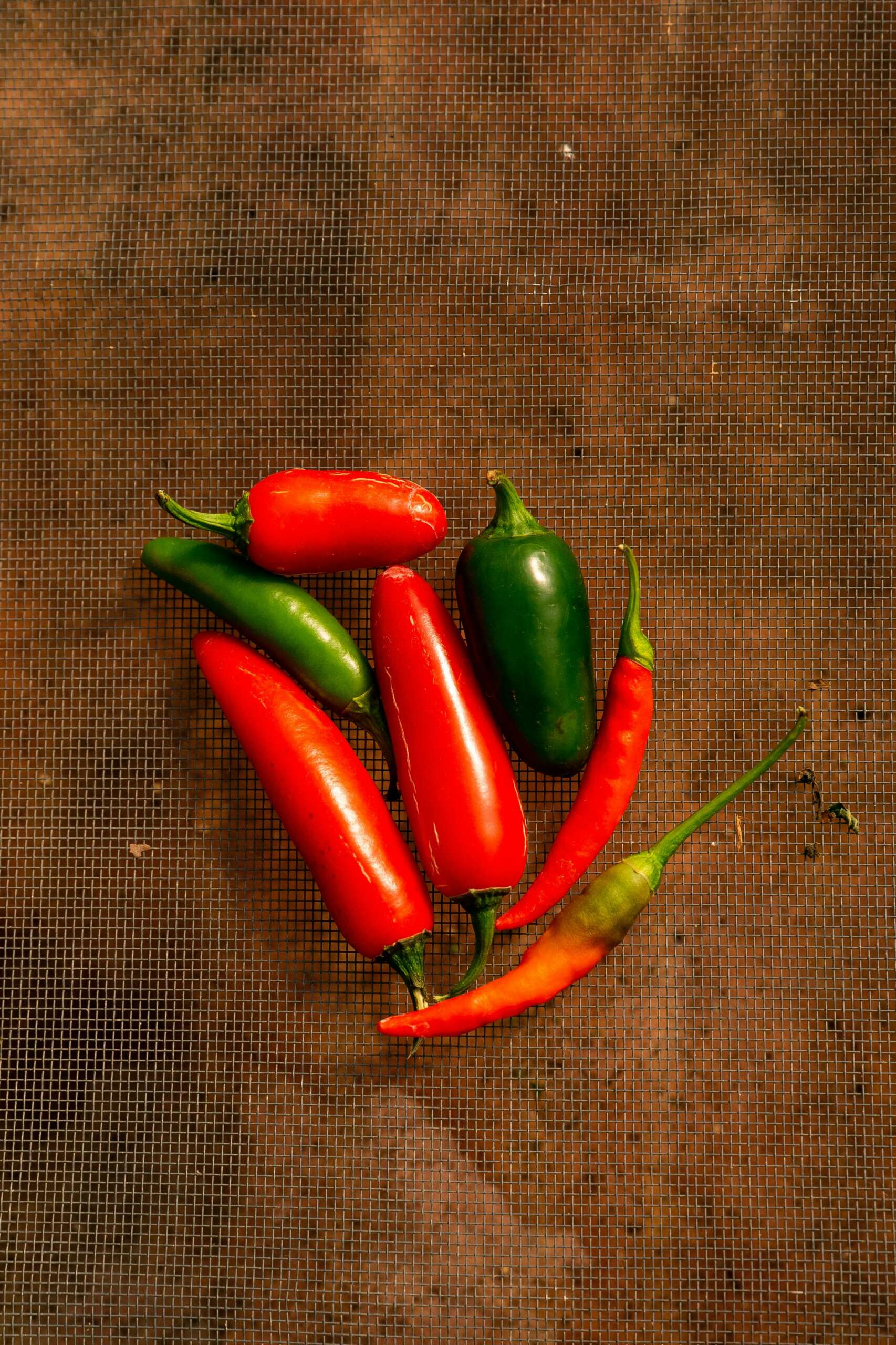 Close-up of vibrant red and green chili peppers on a rustic surface, capturing freshness.